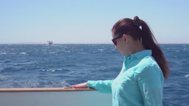 Menina em óculos de sol flutua em um iate no mar — Vídeo de Stock
