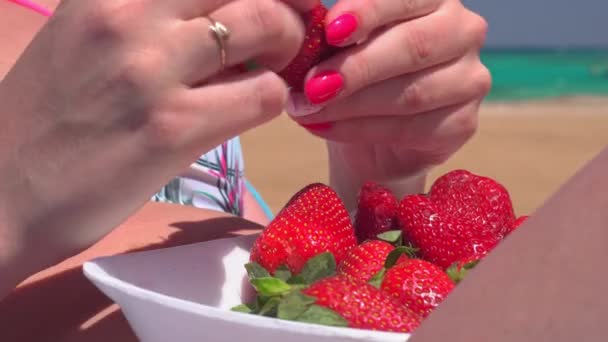 Meisje dat aardbeien eet op het strand — Stockvideo