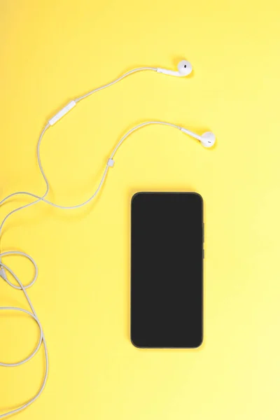 Black Mobile Phone White Headphones Yellow Background Close Top View — 图库照片