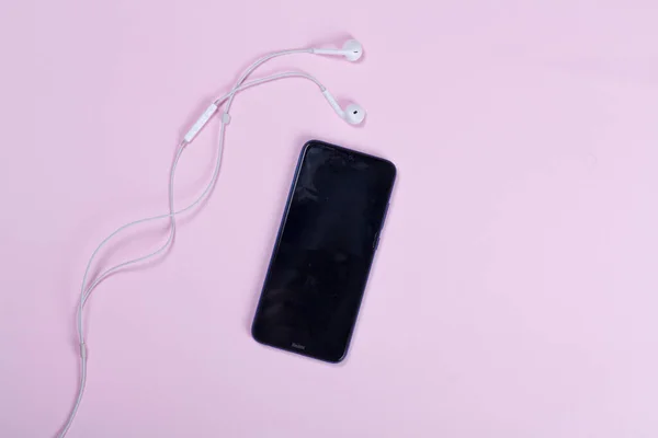 Black Mobile Phone White Headphones Light Pink Background Close Top — 图库照片