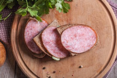 Ahşap mutfak tahtasında sosisli ve otlu sandviçler.