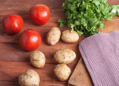 Yuvarlak genç patatesler ve kırmızı domatesler ahşap arka planda, yakın çekim üst manzara