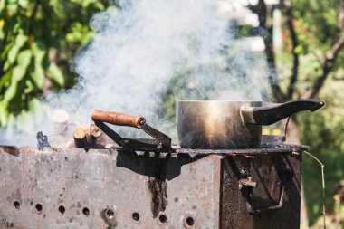 Tarlada ızgarada yuvarlak demir bir tencerede ısıtma suyu. Açık hava yemekleri.