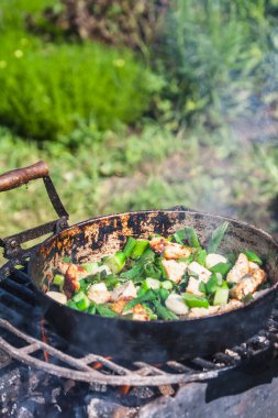 Tarlada ızgarada yemek pişirmek. Sebzeler ve kıyma eski bir tavada yakın plan.