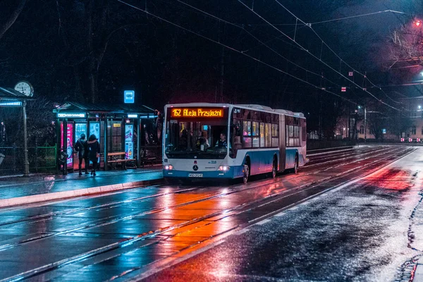克拉科夫市克拉科夫街的巴士站和一辆晚上的公共汽车在雨湿路上拍摄的霓虹灯照片 充满了倒影 — 图库照片