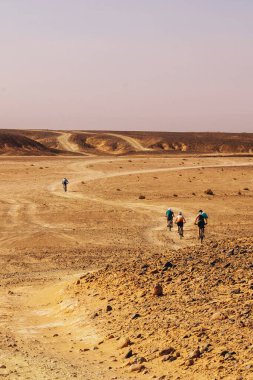 Bir grup bisikletçi uçsuz bucaksız solgun gökyüzünün altında kayalık Sahra çöllerinde yol alıyor. Yüksek perspektiften çekiliyor, dayanıklılık, izolasyon ve uzun mesafeli macera yolculukları gerçekleştiriyor..