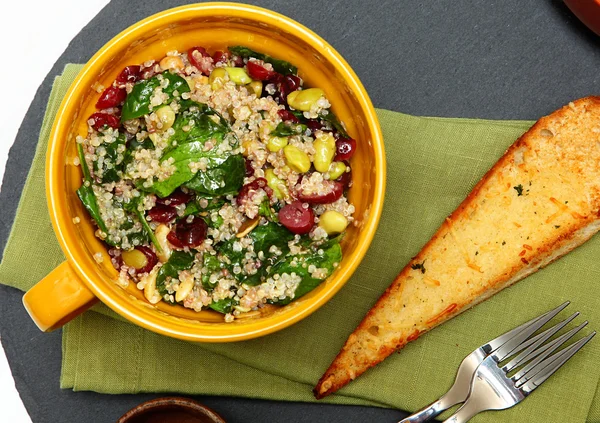 Quinoa špenát brusinkový salát a česnekovými toasty na stole. — Stock fotografie