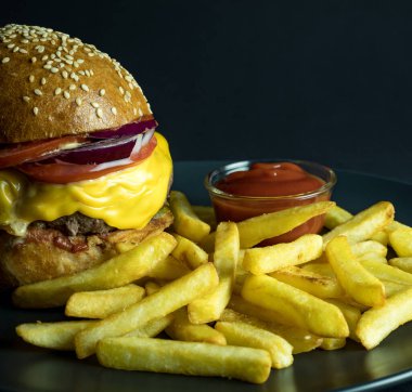 Patates kızartması ve siyah üzerine ketçap dökülmüş hamburgerle kapat.