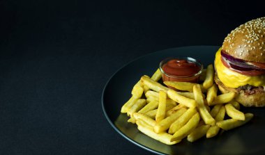 Patates kızartması ve siyah üzerine ketçap ile hamburger manzarasını kapat.