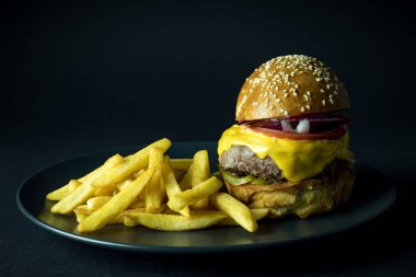 Siyah üzerine izole edilmiş patates kızartmalı leziz çizburgerin yakın görüntüsü