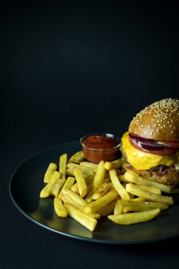 Lezzetli çizburger, patates kızartması ve siyah üzerine izole edilmiş domates sosu.