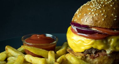 Ev yapımı, susamlı çizburger, patates kızartması ve siyah üzerine ketçap.