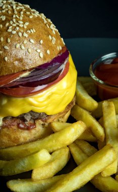 Domates soslu hamburger ve siyah üzerine izole edilmiş patates kızartması.