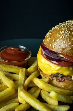 Domates soslu hamburger ve siyah üzerine izole edilmiş patates kızartması.