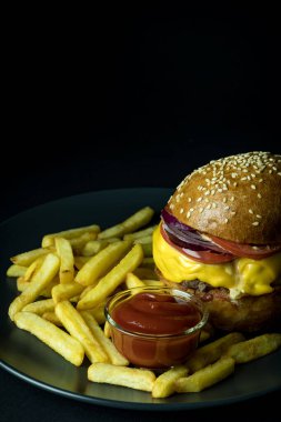 Patates kızartması ve siyah üzerine izole edilmiş lezzetli çizburgerle ketçapı kapat.