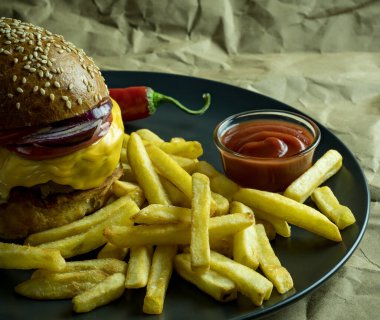 Patates kızartmalı hamburger, domates sosu ve kağıt üzerinde kırmızı biber.