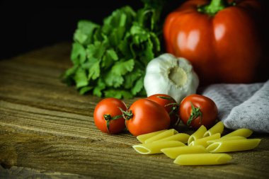 Tahta masadaki havlunun yanında taze kiraz domatesleri ve çiğ makarna.