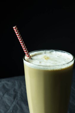 Siyah arka planda pipet içilen bardakta sütlü kahveyi kapat