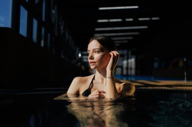 Jakuzide kaplıca kompleksinde oturan esmer kadının portresi