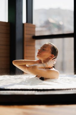 Kaplıcadaki jakuzide dinlenirken ıslak saçlara dokunan kadın.