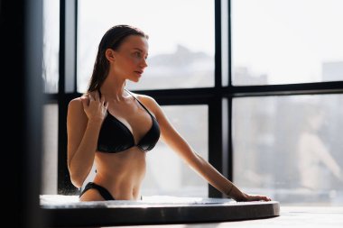 Mayolu esmer kadın modern spa merkezinde jakuzide dinleniyor.