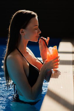 Havuz başında spa merkezinde limonata içen seksi kadın.