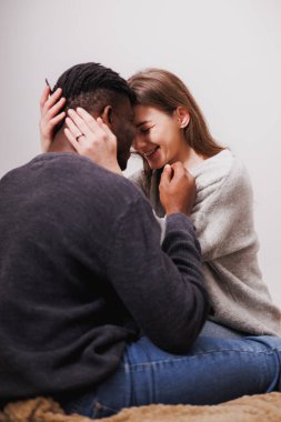 Mutlu, genç, etnik çeşitlilikte bir çift evde yatakta sarılıyor.