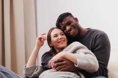 Gündelik giysiler içinde gülen ve evde sarılan çift.