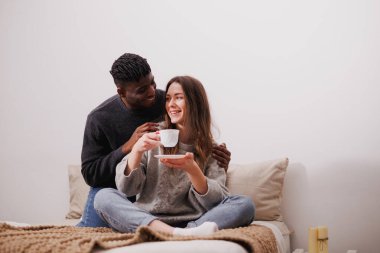 Gülümseyen Afrikalı Amerikalı bir adam kız arkadaşına sarılıyor.