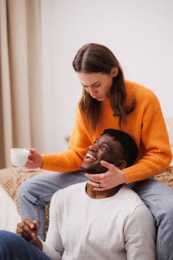 Kahveli genç çift yatak odasında eğleniyor.