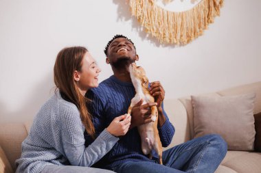 Güler yüzlü çift akşamları kanepede köpekle oynuyorlar.