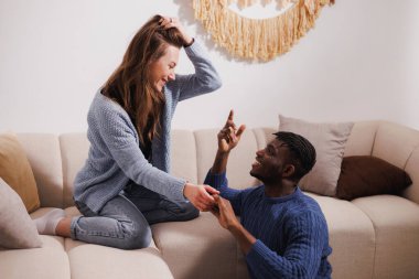 Gülümseyen, etnik çeşitlilikte çiftler evde el ele tutuşuyorlar.