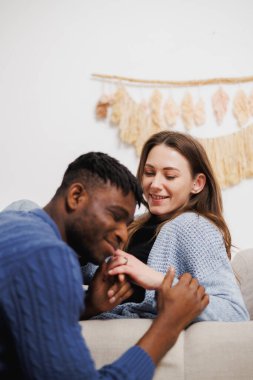 Gülümseyen kadın evde Afrikalı Amerikalı erkek arkadaşının elini tutuyor.