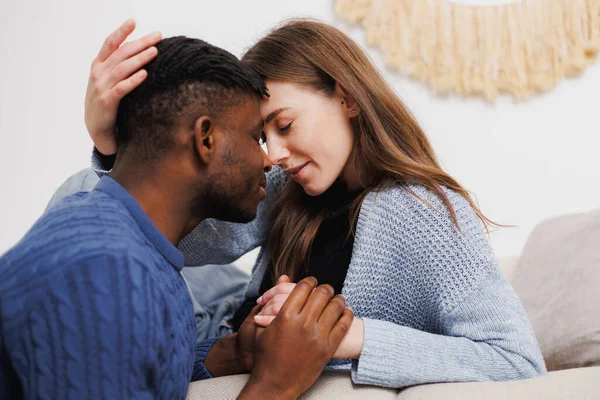 Evde el ele tutuşan çok ırklı romantik çiftin portresi.