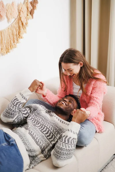 Evdeki koltukta el ele tutuşan neşeli romantik çift.