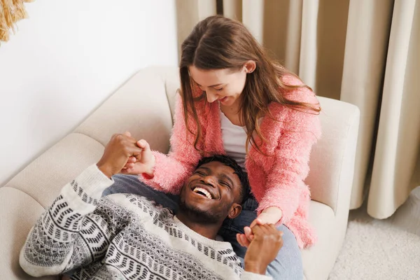 Gülen, etnik çeşitlilikte ve romantik çift evdeki kanepede dinleniyor.