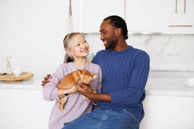 Irklar arası genç çift birbirlerine bakıyor ve evde chihuahua köpeği tutuyorlar.