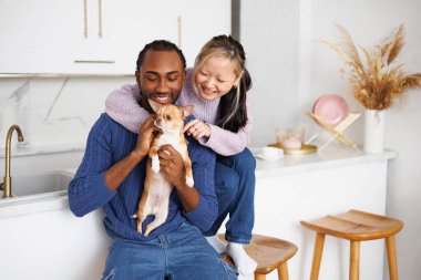 Modern mutfaktaki gülümseyen, ırklar arası bir çiftin evcil köpeği.