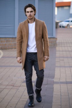 Şehir caddesinde yürürken kameraya bakan şık bir adam.