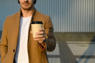 Açık havada paltolu bir adamın elinde kahve kırıntısı.