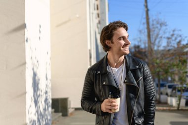 Elinde kağıt bardak tutan şık bir adam ve sabah şehir sokağına bakıyor.