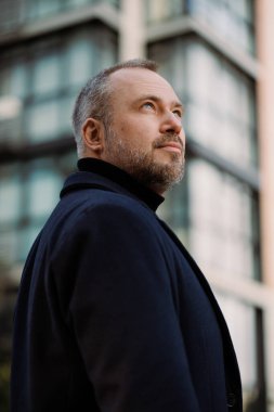 Şehir caddesine bakan zarif ceketli bir adamın portresi.