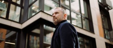 Dışarıdaki binanın yanında duran palto giymiş işadamlarının internet afişi.