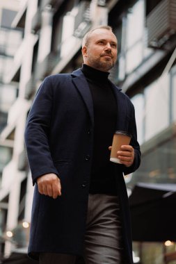 Şehir sokaklarında gezmek için elinde kahve tutan zarif bir adamın portresi.