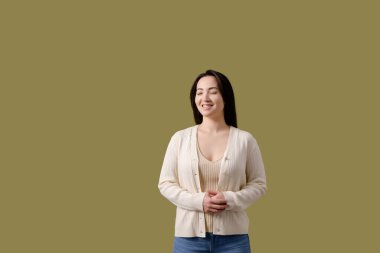 Mutlu Asyalı kadın, günlük giysiler içinde, yeşil alanda tek başına duruyor.