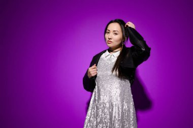 Deri ceketli ve mor elbiseli Asyalı şık bir model.