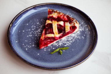 Kafede bir parça vişneli turta, pudra şekeri ve nane yaprağı.