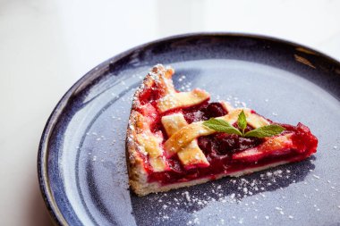 Kahve tabağında nane yaprağı olan lezzetli vişneli tart