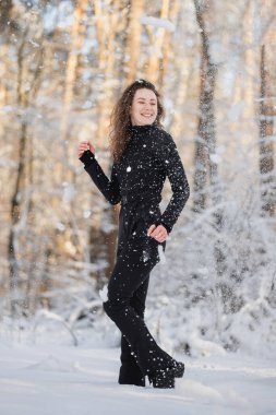 Kar yağarken ormanda duran kayak takımlı neşeli kadın.