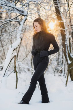 Kış ormanında duran kayak takımı ve eldivenli bir kadın.